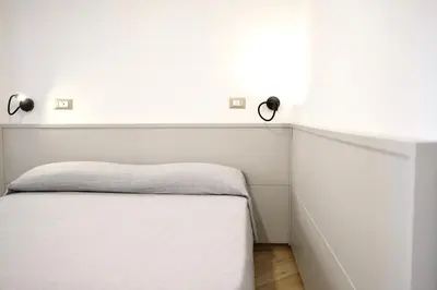 a bed in a room with a white wall at Belmonte Apartments in Palermo