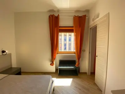 a bedroom with an orange curtain and a window at Belmonte Apartments in Palermo