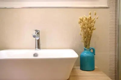 a bathroom with a white sink and a blue vase at Belmonte Apartments in Palermo