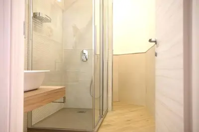 a glass shower in a bathroom with a sink at Belmonte Apartments in Palermo