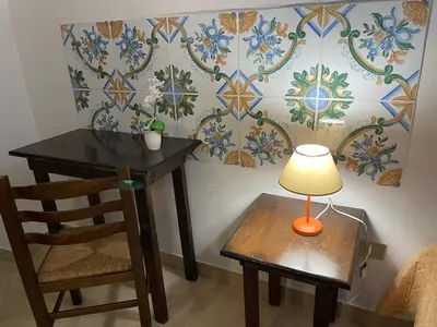 a table with a lamp and a chair in a room at Normanni Central House in Palermo
