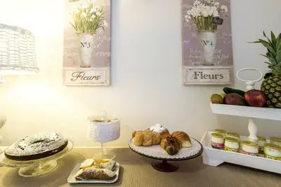 a table with a tray of pastries and flowers on it at Gran Cancelliere Apartment Parking in Palermo