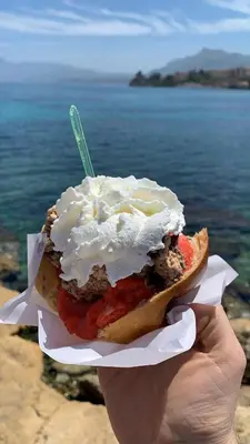 a hand holding a sandwich with whipped cream and tomatoes at VENTO DI SCIROCCO CASA VACANZE A POCHI METRI DAL MARE in Santa Flavia