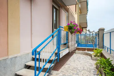 a blue railing on a building with a balcony with flowers at VENTO DI SCIROCCO CASA VACANZE A POCHI METRI DAL MARE in Santa Flavia