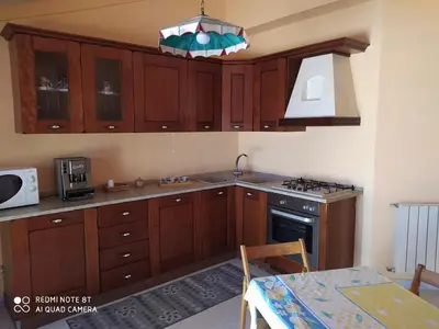 a kitchen with wooden cabinets and a stove top oven at Casa vacanze a Serra Scirocco in Trabia