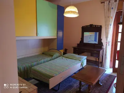 two beds in a room with a tv and a table at Casa vacanze a Serra Scirocco in Trabia
