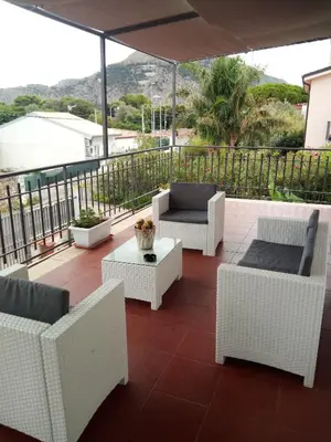 a patio with chairs and tables and an umbrella at Appartamento a Mondello in Mondello