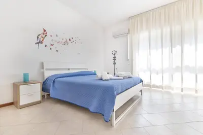 a white bedroom with a blue bed and a window at La Lumia - Al Politeama in Palermo