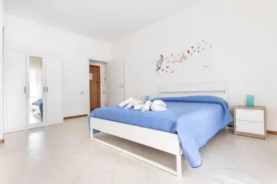 a white bedroom with a bed with blue sheets at La Lumia - Al Politeama in Palermo