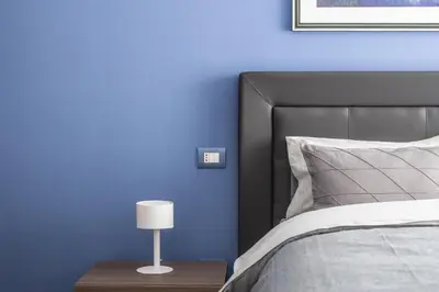a blue bedroom with a bed and a lamp at M'Place Apartments in Palermo