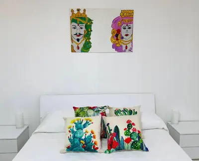 a bedroom with a white bed with two pictures on the wall at Made In Sicilia -IN CENTRO, ARIA CONDIZIONATA e NO ZTL- CITY CENTRE, AIRCON and NO LTZ in Castellammare del Golfo