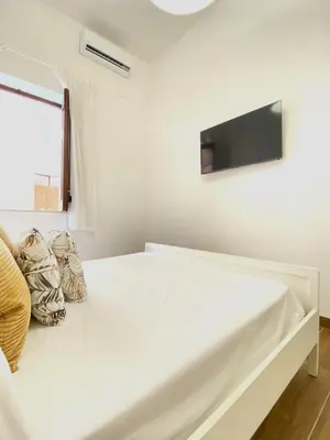 a white bedroom with a bed and a flat screen tv at Medusa -IN CENTRO, ARIA CONDIZIONATA e NO ZTL -CITY CENTRE, AIRCON, NO LTZ in Castellammare del Golfo
