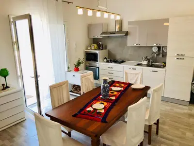 a kitchen with a wooden table and white cabinets at VILLA OASI a 50 mt dalla spiaggia in Alcamo Marina