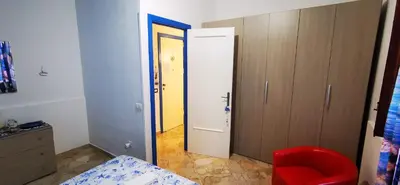 a room with a bedroom with a door and a red chair at Casa Giusi in Sferracavallo