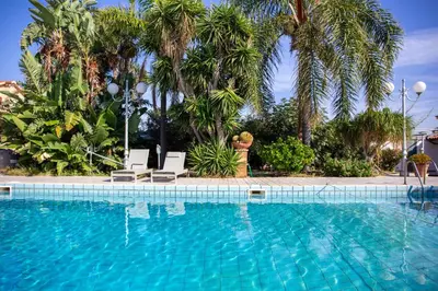 a swimming pool with two chairs and palm trees at Solemar Sicilia - Villa Anastasia in Ficarazzi
