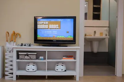 a television on a white stand with two helmets at Paccamora by Maravigghia Palermo in Palermo