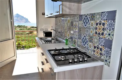 a kitchen with a stove and a tile wall at Casa Vacanze Monte Cofano in Macari