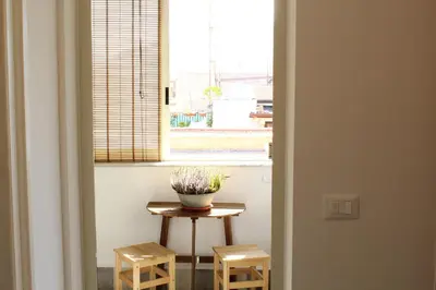 a small table with a vase of flowers on it next to a window at Cosmo Apartment in Palermo