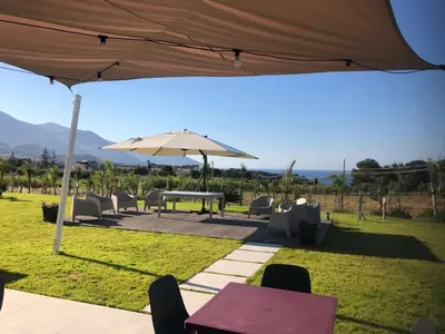 a patio with an umbrella and a table and chairs at Villa NATURE ZAGARA SCOPELLO ZINGARO in Castellammare del Golfo