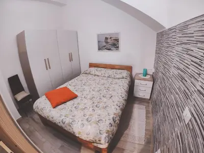 a bedroom with a bed with an orange pillow on it at Casa vacanza Terra Mare in Castellammare del Golfo