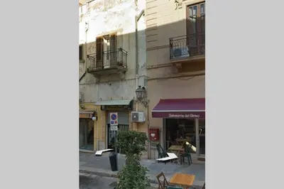 a street corner with a building and tables and chairs at Casa vacanza Terra Mare in Castellammare del Golfo