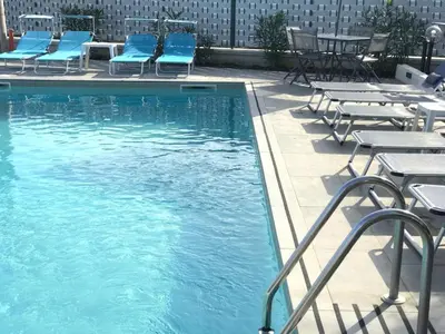 a swimming pool with blue chairs and tables at Villa Mazzamuto in Altavilla Milicia