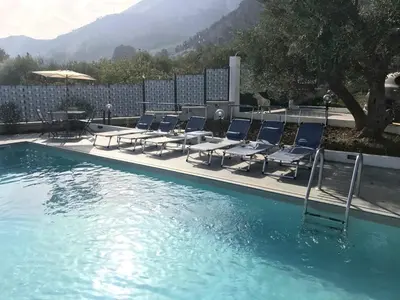 a group of lounge chairs and a pool with a table and chairs at Villa Mazzamuto in Altavilla Milicia