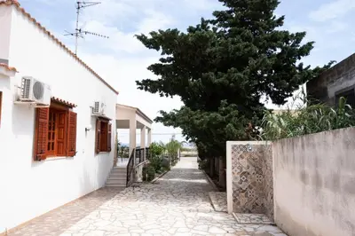 a street with white houses and a tree at Casa Laura di fronte la Tonnara in San Vito lo Capo