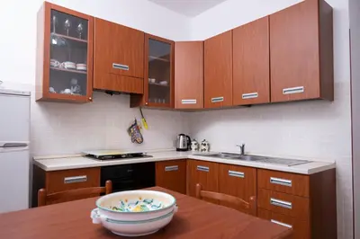 a kitchen with wooden cabinets and a wooden table at Casa Laura di fronte la Tonnara in San Vito lo Capo