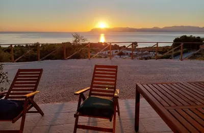 two chairs and a table with a sunset in the background at Villa Futura in Scopello