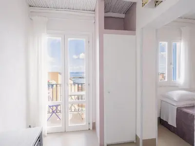 a white bedroom with a view of the ocean at Tannur B&B in Castellammare del Golfo