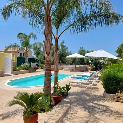 a swimming pool with two palm trees and two chairs at Villa Summer in Trappeto