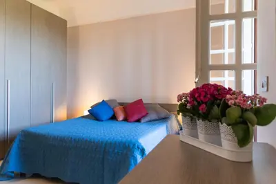 a bedroom with a bed with colorful pillows and a window at Casa Pitea in Mondello