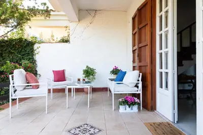 a patio with white chairs and a table at Casa Pitea in Mondello