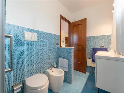 a blue tiled bathroom with a toilet and a sink at Villa with Pool, Pets & WiFi in Misilmeri