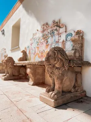 a statue of a lion sitting next to a wall at Villa del Gattopardo in Palermo