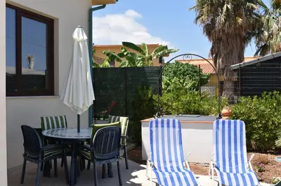 a patio with a table and chairs and an umbrella at In Riva al Mare da Franca in Trabia