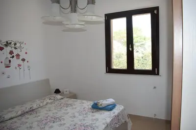 a white bedroom with a bed and a window at In Riva al Mare da Franca in Trabia