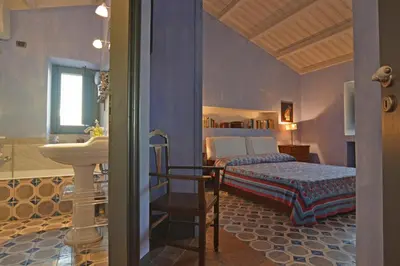 a bedroom with a bed and a sink and a bathroom at Villa con piscina vicino Cefalù (Sanificata) in Gratteri