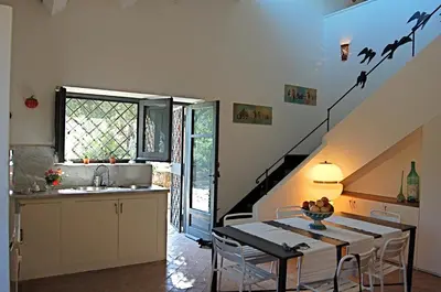 a kitchen and dining room with a table with birds on the wall at Villa con piscina vicino Cefalù (Sanificata) in Gratteri