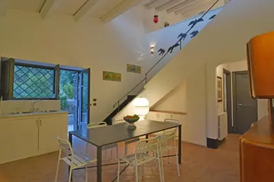 a dining room with a table and chairs and a staircase at Villa con piscina vicino Cefalù (Sanificata) in Gratteri