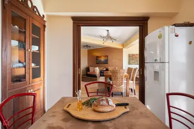 a kitchen and dining room with a table and a white refrigerator at Panoramica Villa con Piscina sul Mare (Sanificata) in Cinisi