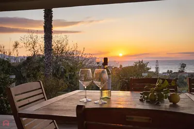 a wooden table with two wine glasses and the sunset at Panoramica Villa con Piscina sul Mare (Sanificata) in Cinisi