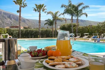a table with food and a pitcher of juice next to a pool at Panoramica Villa con Piscina sul Mare (Sanificata) in Cinisi