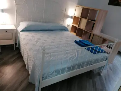 a bedroom with a white bed and a book shelf at Case Vacanze Azzurra, Loredana e Trinacria in Castellammare del Golfo