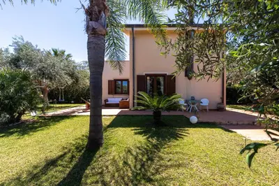 a house with a palm tree in the yard at Deliziosa Villa a 500 metri dal mare con Piscina in Terrasini