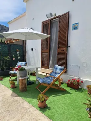 a patio with two chairs and an umbrella at Bea's House in Castellammare del Golfo