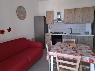 a kitchen with a red couch and a table with chairs at Bea's House in Castellammare del Golfo