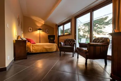 a bedroom with a bed and two chairs and windows at Villa San Lorenzo in Palermo