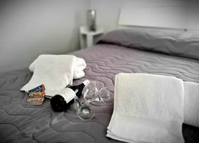 a bed with towels and a glass of wine and towels at SCRUSCIU HOME in Terrasini